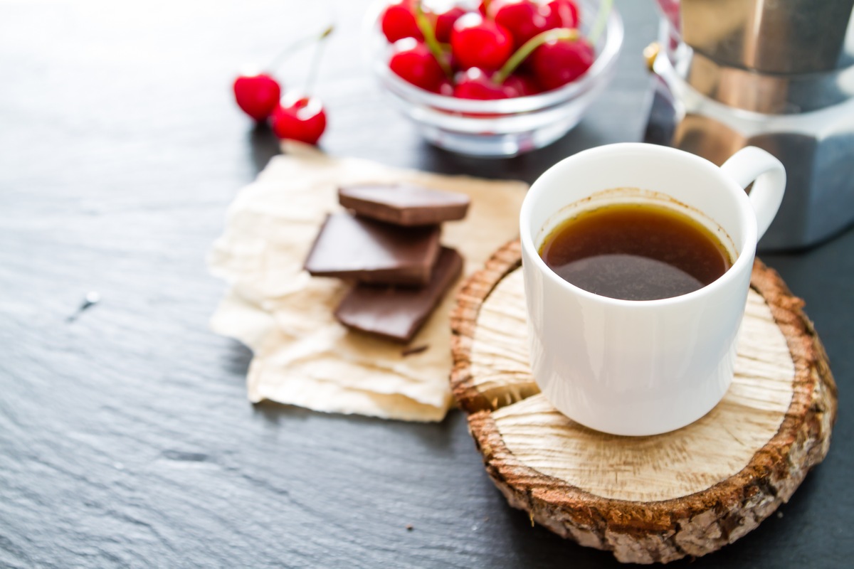 Coffee in white cups on wood boards, chocolate, berries dark stone background